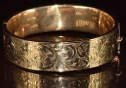 A 9ct gold bangle with engraved scrolling decoration, 27.2g, 6.5 x 5.8cm