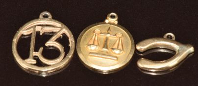 Four 9ct gold charms including wishbone, bell, '13', and Libra scales, 5.4g