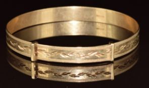 A 9ct gold adjustable bangle with cut out foliate decoration, 7.3g