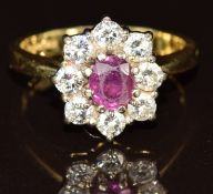 An 18ct gold ring set with an oval cut ruby of approximately 0.6ct surrounded by eight diamonds, the