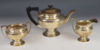 George V hallmarked silver three piece tea set with faceted bodies and pedestal bases, Birmingham