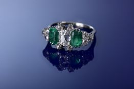 An 18ct gold ring set with a cushion cut diamond of approximately 1.2ct, two emerald cut emeralds
