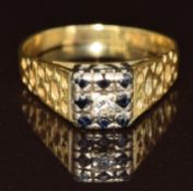 An 18ct gold ring set with a diamond and sapphires in a square setting, 3.8g, size O