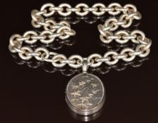 A late Victorian silver locket with applied gold floral decoration (6 x 3.3cm) on silver chain