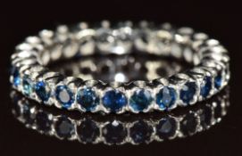 A white metal eternity ring set with round cut sapphires, 6.5g, size P