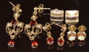 Four pairs of 9ct gold earrings including two set with garnets, one opal and the other pair tri-