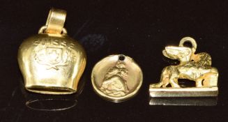 Three yellow metal charms in the form of a winged lion, Suisse bell and a St Christopher, 5.7g