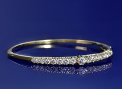 An 18ct gold bangle set with seventeen round cut diamonds, the total diamond weight approximately