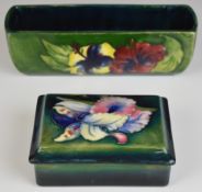 Moorcroft covered box decorated in the Orchid pattern and a trough with Hibiscus decoration,