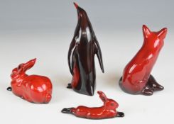 Four Royal Doulton flambé animals comprising seated fox, two hares and a penguin, tallest 14.5cm