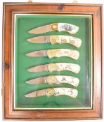 Framed set of six Franklin Mint hunting / shooting / fishing themed folding knives, L17cm, the