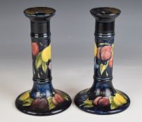 Moorcroft pair of signed candlesticks decorated in the Wisteria pattern, H19cm