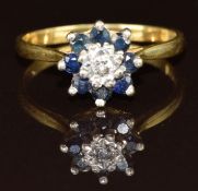 An 18ct gold ring set with a diamond surrounded by sapphires in a cluster, 2.8g, size O