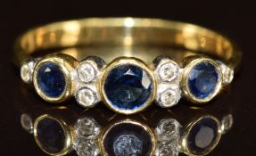 An 18k gold ring set with three round cut sapphires and diamonds, 2g, size M