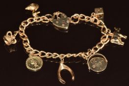 A 9ct gold charm bracelet with seven 9ct gold charms including St Christopher, cow, duck, etc, 17.6g