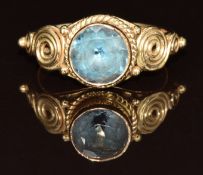 An 18ct gold ring set with a blue topaz with swirling decoration to the shoulders, 4g, size J