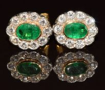 A pair of 18ct gold earrings each set with an oval cut emerald of approximately 0.45ct surrounded by