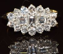 An 18ct gold ring set with three baguette cut diamonds surrounded by round cut diamonds, the total