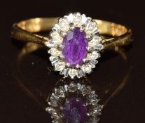 An 18ct gold ring set with an oval cut amethyst surrounded by diamonds, 2.9g, size M