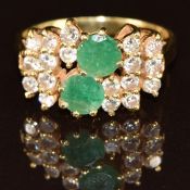 An 18ct gold ring set with two round cut emeralds and diamonds, 4.5g, size K