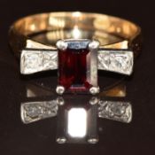 An 18k gold ring set with an emerald cut garnet and two diamonds, 3.8g, size N