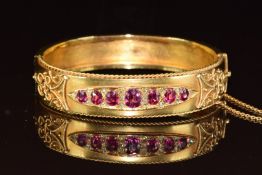 Victorian 15ct gold bangle set with seven oval cut rubies and sixteen rose cut diamonds, the largest