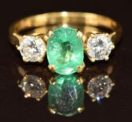 An 18ct gold ring set with an oval cut emerald of approximately 1.2ct and two diamonds each