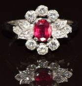 An 18ct white gold ring set with an oval cut ruby of approximately 0.5ct surrounded by six