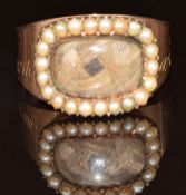 A 9ct gold mourning ring set with hair in a locket section surrounded by split pearls, engraved '