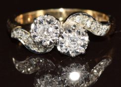 A 9ct gold ring set with two diamonds in a twist setting and with further diamonds to the shoulders,