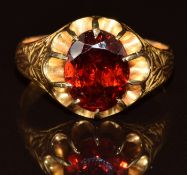 Victorian 15ct gold ring set with an oval cut garnet with embossed decoration to the shoulders,