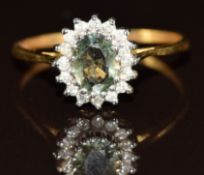 A 9k gold ring set with an oval cut green sapphire surrounded by diamonds, 2.3g, size R