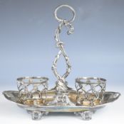 French 950 grade silver twin bottle stand with scroll handle, shaped edge and raised on four feet,
