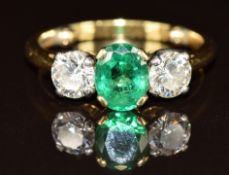 An 18ct gold ring set with an oval cut emerald of approximately 1ct and two round cut diamonds of