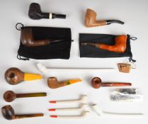 Fourteen clay, briar and specimen wood smoking pipes including Dawn Mist, some signed with motifs,