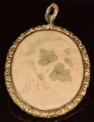 Victorian locket with engraved floral and foliate border set with a piece of fabric reading '