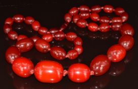 A cherry amber necklace made up of 43 graduated oval beads, largest bead 3.2 x 2.5cm, smallest
