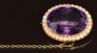 A c1900 15ct gold brooch set with an oval cut amethyst (21.8 x 16.5 x 10.2mm) surrounded by seed