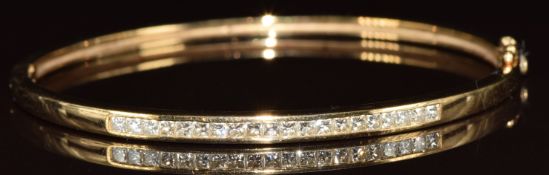 A 9k gold bangle set with twenty princess cut diamonds, the total diamond weight approximately
