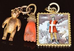 A c1900 charm/ pendant set with coral in the form of a hand/ fist, yellow metal Teddy bear charm and