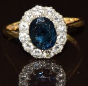 An 18ct gold ring set with an oval cut sapphire surrounded by diamonds, 3.4g, size L