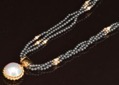 A triple strand of hematite, pearl and 18k gold beads with an 18k gold clasp and 18k gold pendant