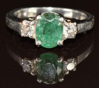 A platinum ring set with an oval cut emerald of approximately 1.2ct and two diamonds each