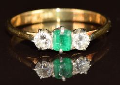 An 18ct gold ring set with an emerald cut emerald of approximately 0.2ct and two round cut