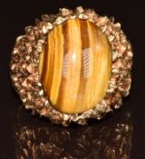 A 1970s 9ct gold ring set with a tiger's eye cabochon, with textured pierced shoulders, 8.7g, size P