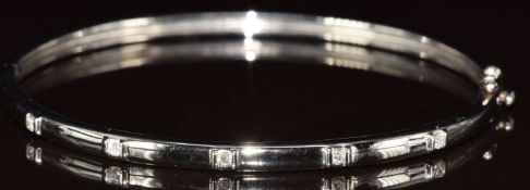 A 9k white gold bangle set with five round cut diamonds, each approximately 0.02ct, 12g, 5.8 x 5.