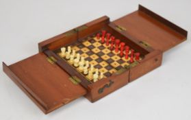 An early 20th century travel chess set with stained and natural bone pieces, housed in a hinged