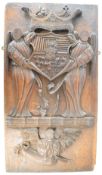 Continental carved oak armorial panel comprising a heraldic coat of arms being help by two winged