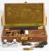 A 12 bore shotgun cleaning kit with ebony and brass rods, chrome oil bottles etc, unused in hardwood