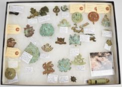 Framed display of WW1 battlefield find badges, most annotated including Somme, Neuve Chapelle and